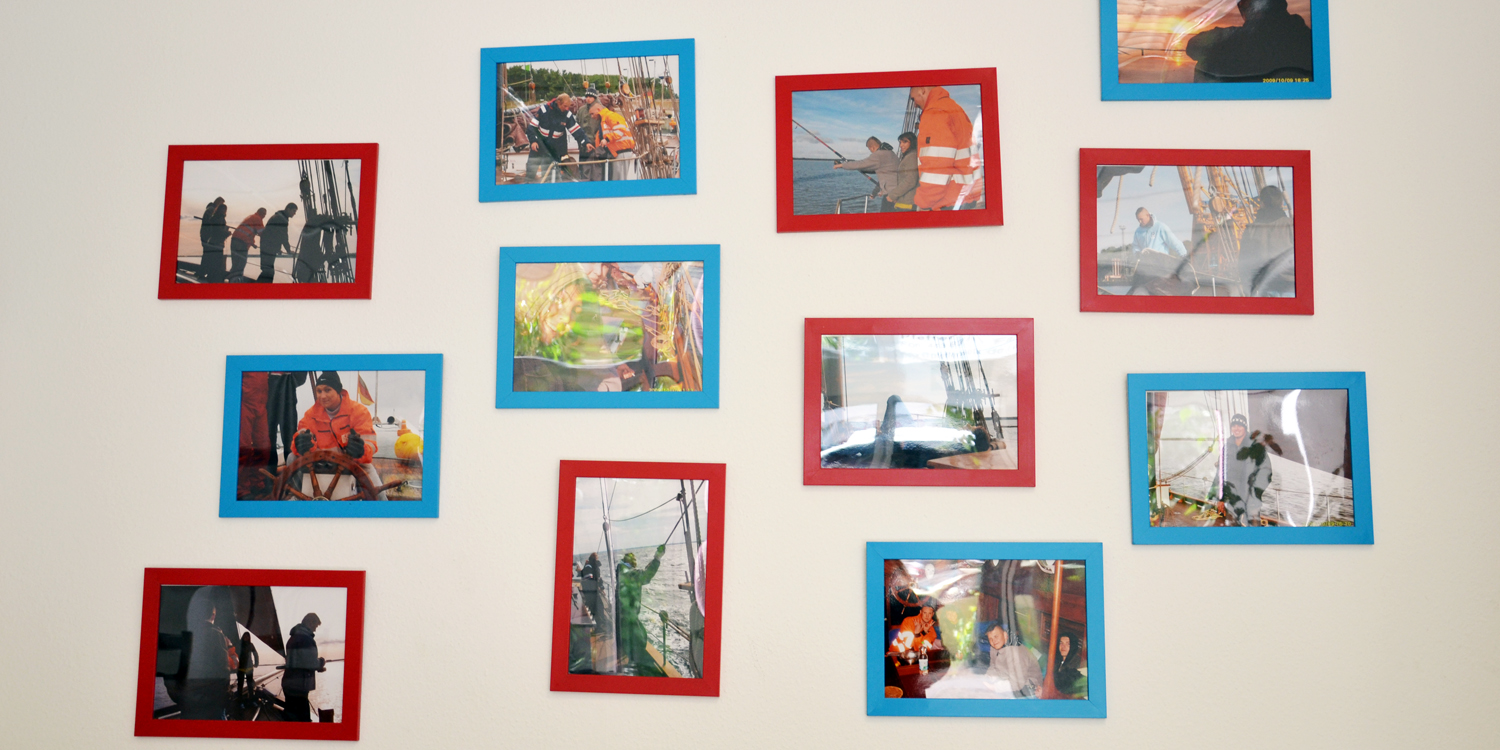 Mehrere Fotos an einer Wand, die Personen auf einem Schiff zeigen