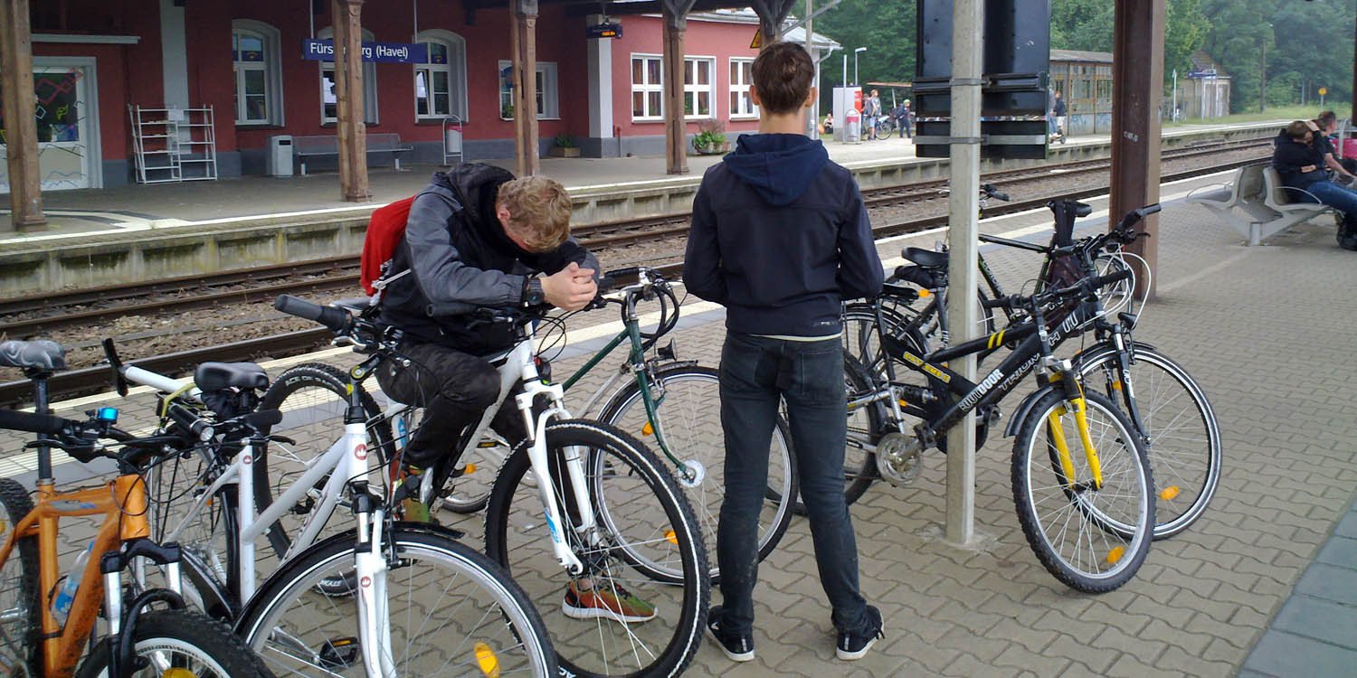 Zwei Personen stehen an einem Bahnhof, auf dem mehrere Fahrräder stehen