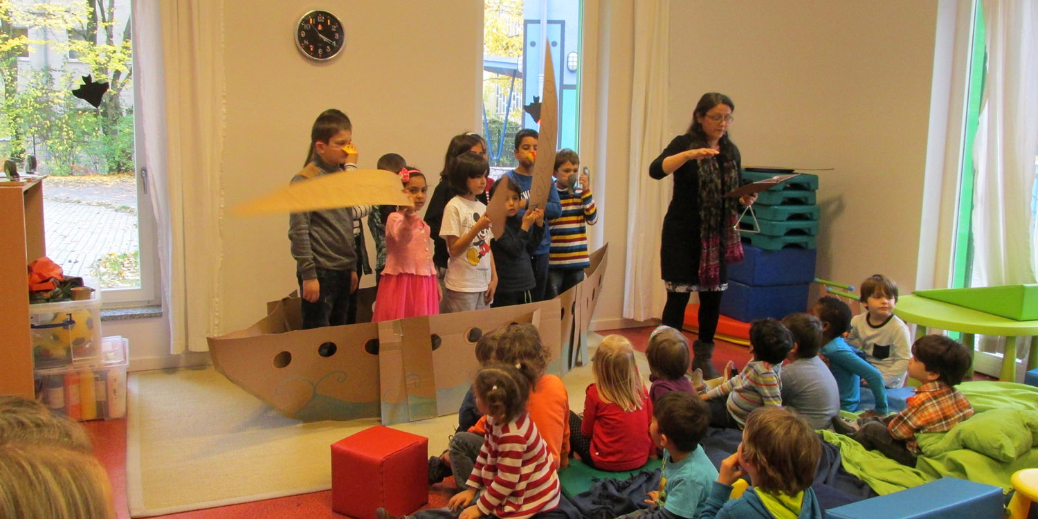 Einige Kinder schauen anderen Kindern beim Spielen einer Aufführung mit einem Boot zu