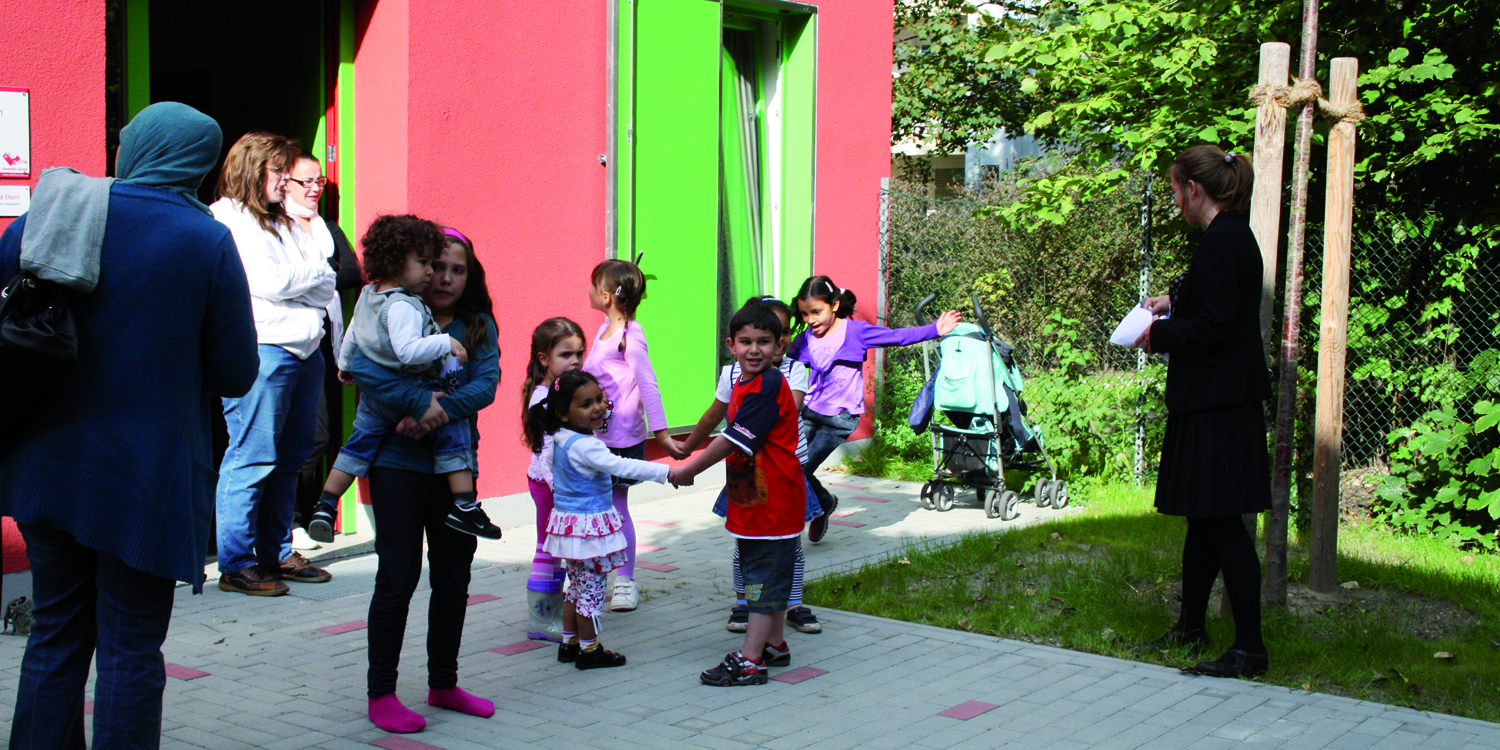 Mehrere Kinder stehen in der Mitte und vier Erwachsene stehen um die Kinder