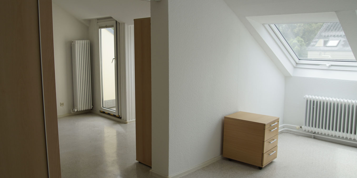 Zwei Räume mit einer Dachschräge. In einem Raum ist ein kleiner Schrank und in dem anderen ist ein großer Schrank