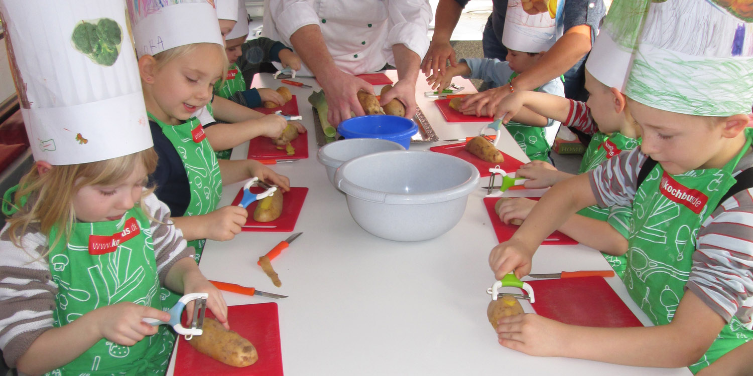 Mehrere Kinder, die Kartoffeln schälen unter Aufsicht