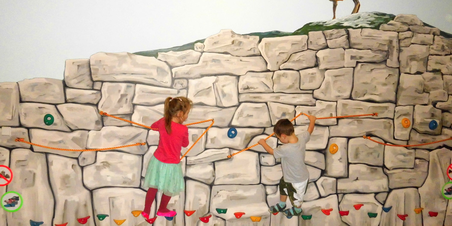 Zwei Kinder klettern an einer kleinen Kletterwand
