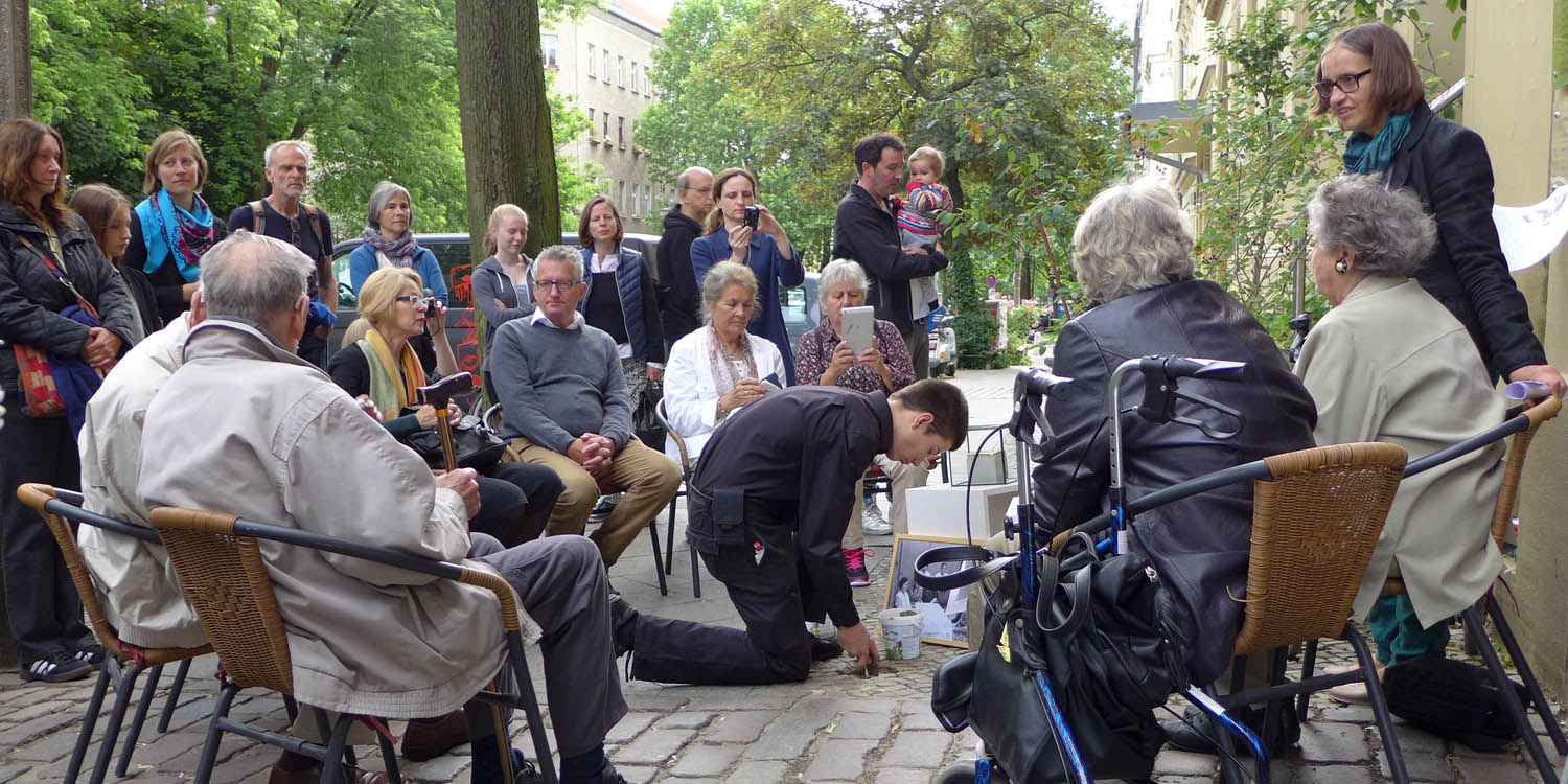 Menschen stehen und sitzen vor einer knienden Person