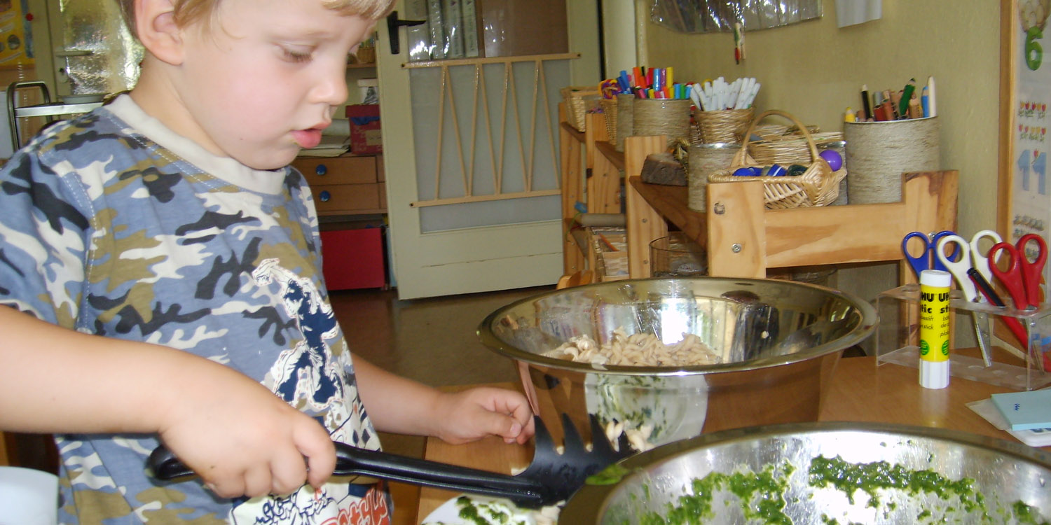 Kind macht sich Nudeln auf einen Teller