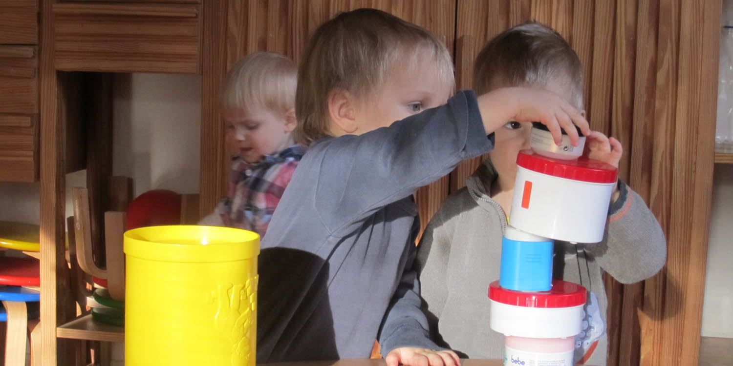 Zwei Kinder bauen einen Turm aus Behältern