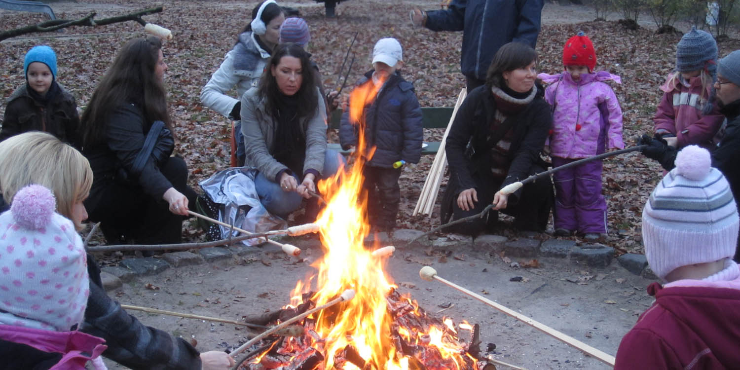 Eltern und Kinder beim Stockbrot grillen am Lagerfeuer