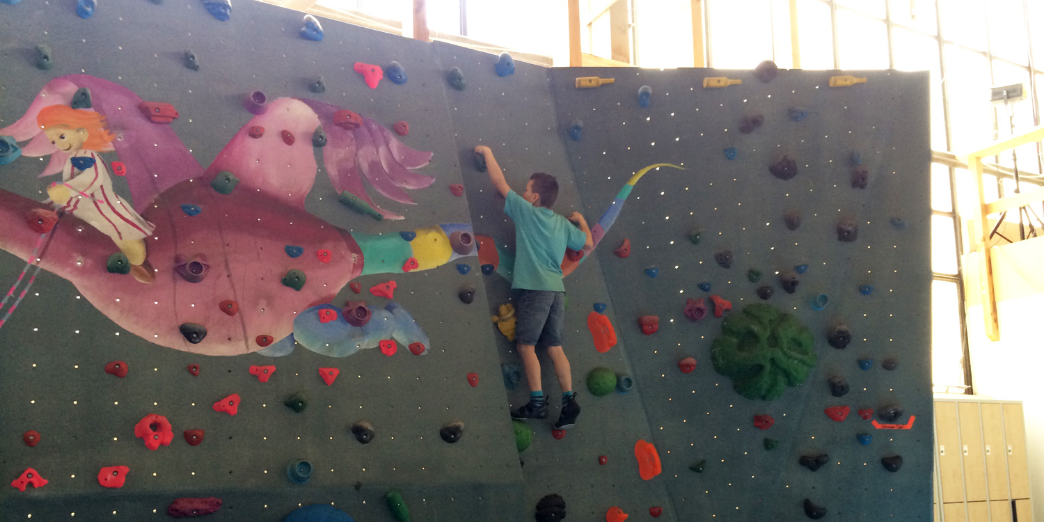 Ein Junge klettert auf einer Kletterwand