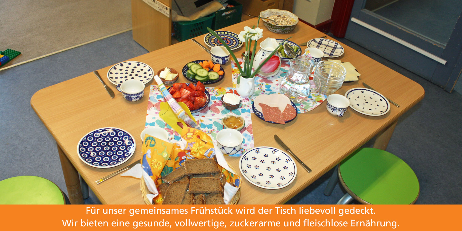 Auf einem liebevoll gedeckten, viereckigen laden Obst, Gemüse, vegetarische Wurst und Brot zu einem gesunden Frühstück ein.