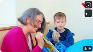 Eine Frau hält ein Buch in der Hand und lächelt. Ein Junge sieht zu dem Buch.