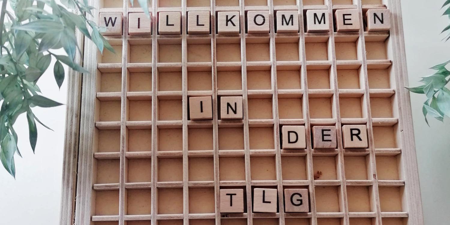 In einem Buchstabenfeld steht geschrieben: Willkommen in der TLG