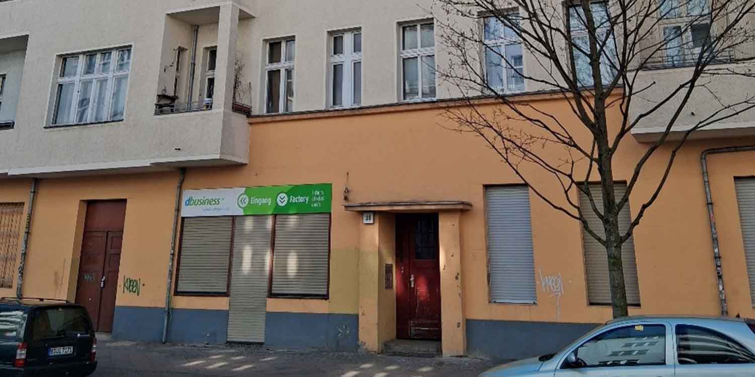Ein Hauseingang in der Schieritzstraße 38. Die untere Etage ist orange; darüber befinden sich Wohnungen in hellbeige angemalten Etagen.