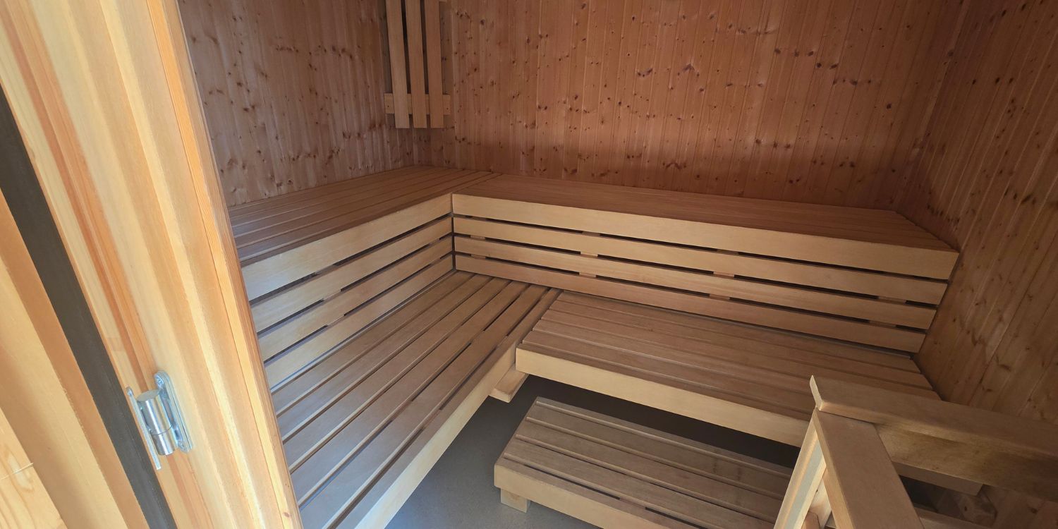 Innenraum einer Sauna mit Holzbänken auf zwei Ebenen.