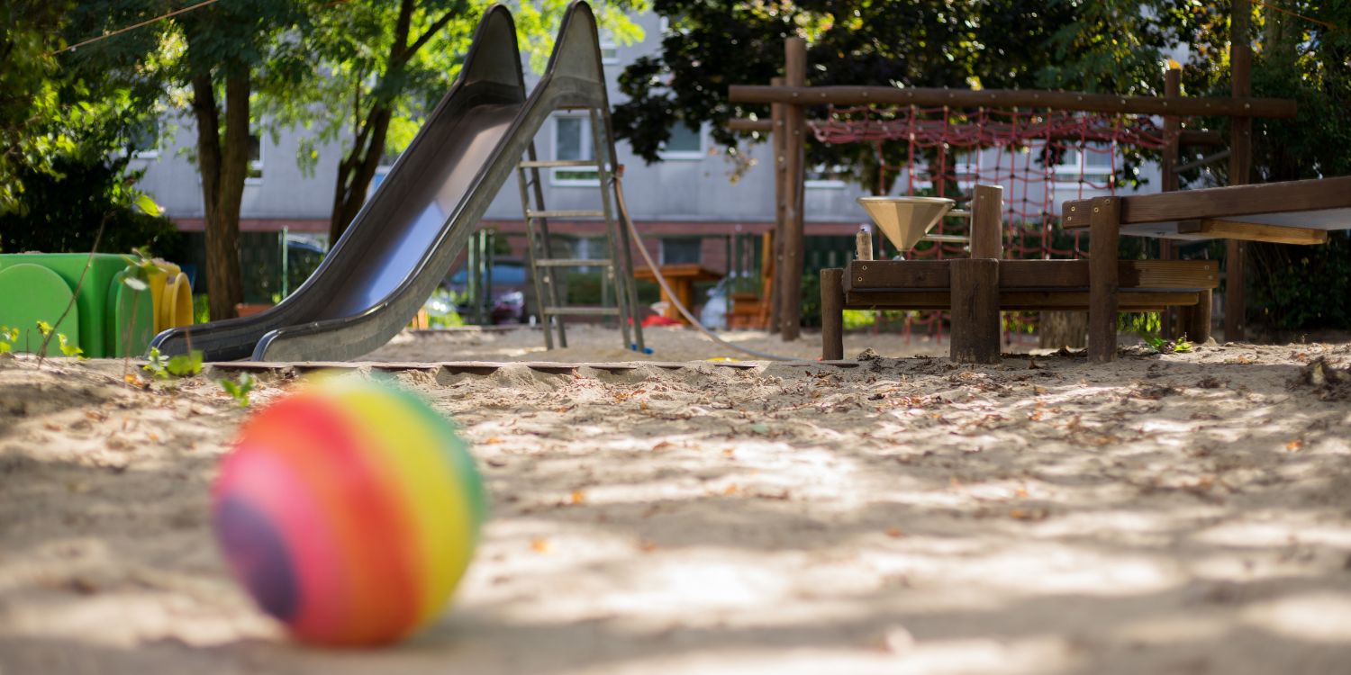 Im Vordergrund liegt ein bunter Ball. Im Hintergrund steht ein Klettergerüst.